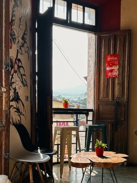 Ventana del café con banquitos, plantas y vista a las montañas